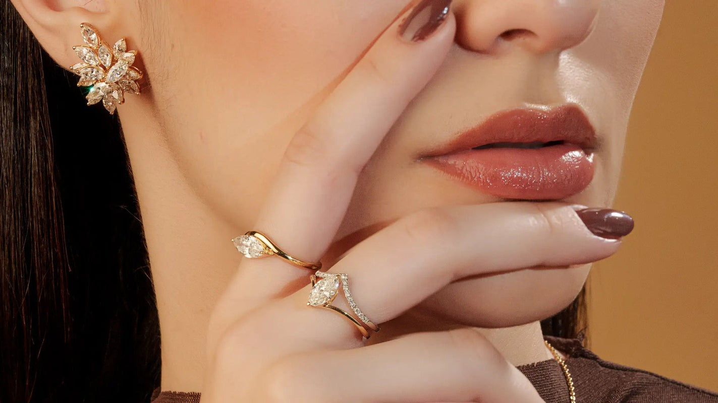 Close-up of a woman's hand wearing gold rings with a neutral background